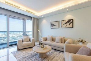 Una sala de estar moderna con un ventanal grande, dos sofás, una mesa de centro y dos cuadros enmarcados en la pared.
