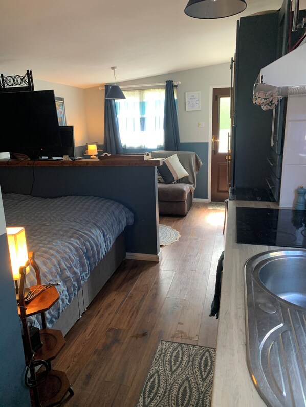 A bedroom with a bed, bedside table, lamp, and a TV.