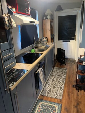 A compact kitchen with a stove, sink, and cabinets, a small refrigerator, and a microwave.