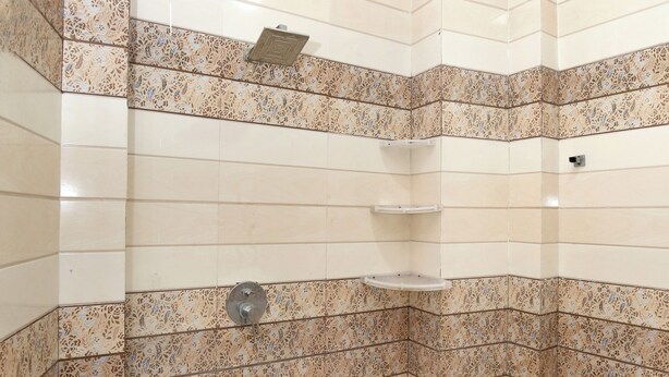 A corner shower with tiled walls and floor, a showerhead, and a shelf. - Hotel 3 Bros Near Airport Road Sector 70 Mohali Chandigarh (Mohali)