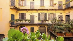 Un edificio a più piani con balconi, piante in vaso e un piccolo giardino.