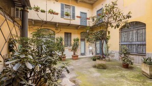 Un cortile con piante in vaso, una scala e un edificio con balconi.