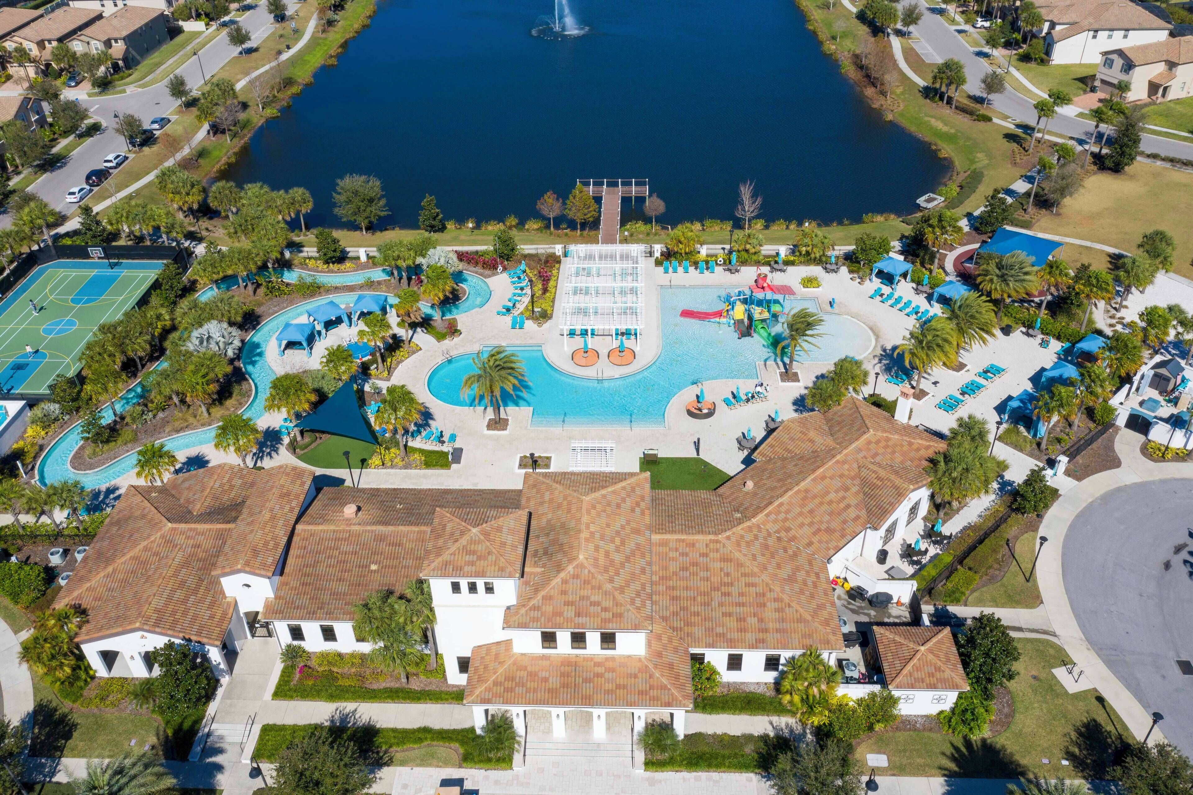 Eine Vogelperspektive zeigt ein Resort mit einem großen zentralen Pool, einem Tennisplatz und einer Fontäne.