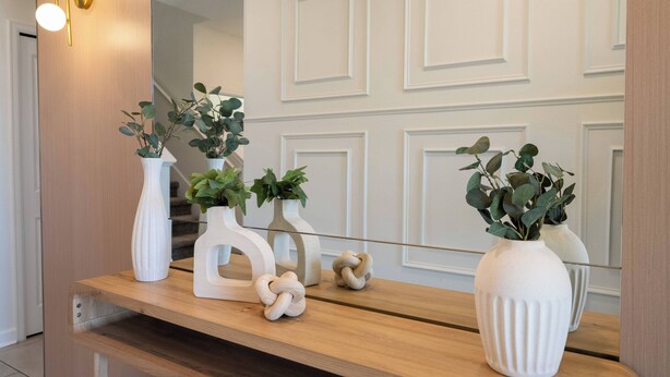 A wooden console table with white vases and a plant, reflecting a mirror and a wall with paneling. - Stunning 6 bedrooms Storey Lake (Kissimmee)