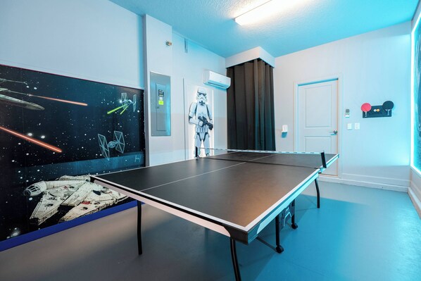 A ping pong table in a room with Star Wars-themed decor, including a mural of spaceships and a Stormtrooper figure. - Stunning 6 bedrooms Storey Lake (Kissimmee)