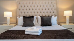 A neatly made bed with a tufted headboard, two bedside lamps, and a folded towel on the bed. - Stunning 6 bedrooms Storey Lake (Kissimmee)