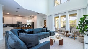 A spacious living area with a large blue sofa, a coffee table, and a dining area. - Stunning 6 bedrooms Storey Lake (Kissimmee)