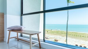 A room with a large window overlooking a beach.