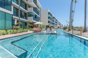 Et moderne hotel med swimmingpool, udendørs siddepladser og palmer.