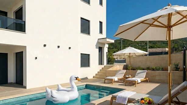 A modern pool area with lounge chairs, a swan float, and umbrellas. - Two-bedroom family rooms apartment Casa Del Mar 4 with private balcony (Stara Novalja)