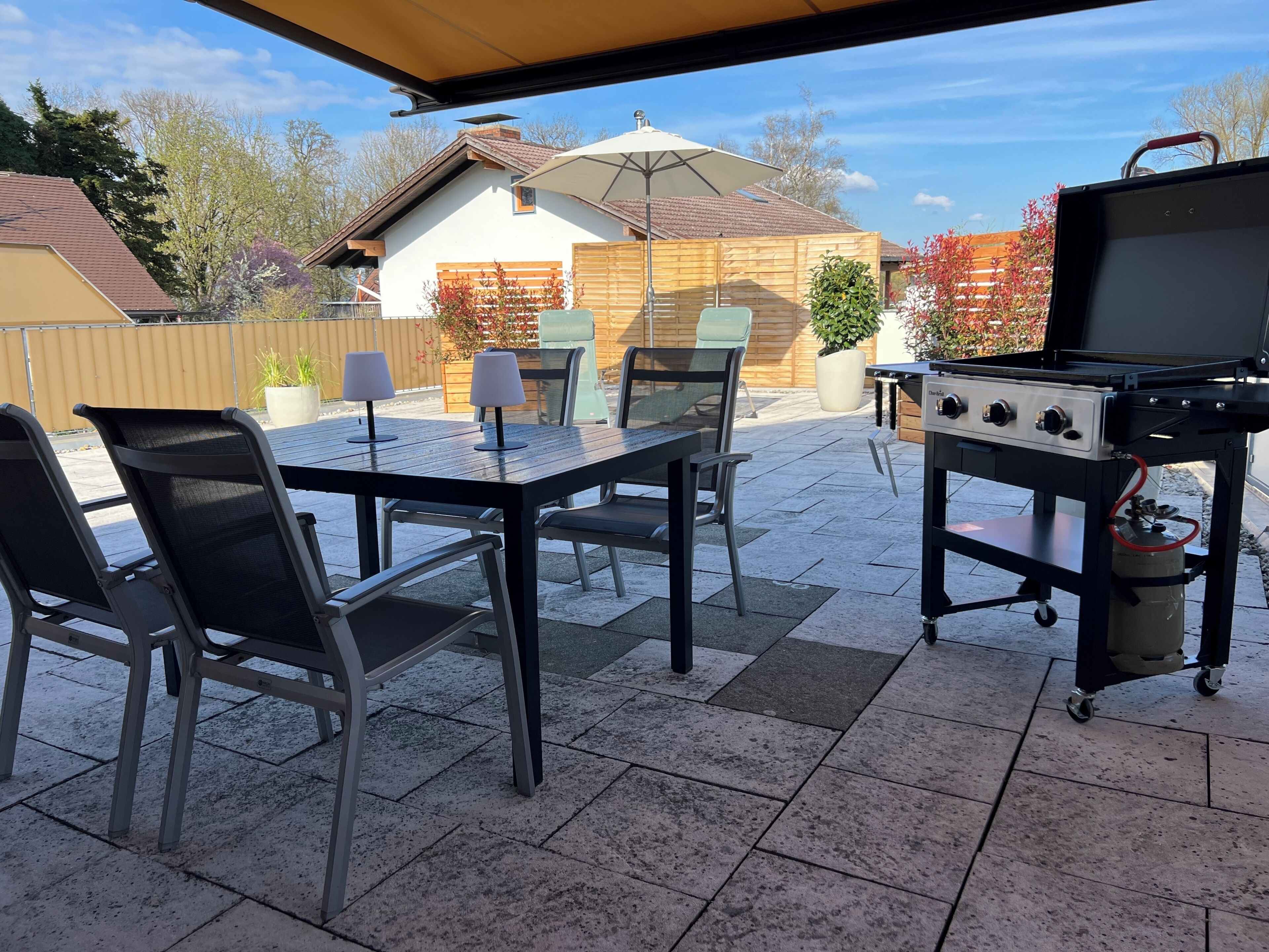 An outdoor patio with a grill, chairs, and a table.