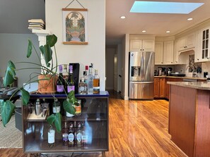 Una cucina moderna con isola integrata, elettrodomestici in acciaio inossidabile e diverse bottiglie sul bancone.