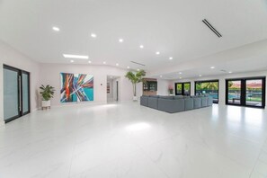 A spacious lobby with a modern design, featuring a large abstract painting, a seating area, and large windows offering a view.
