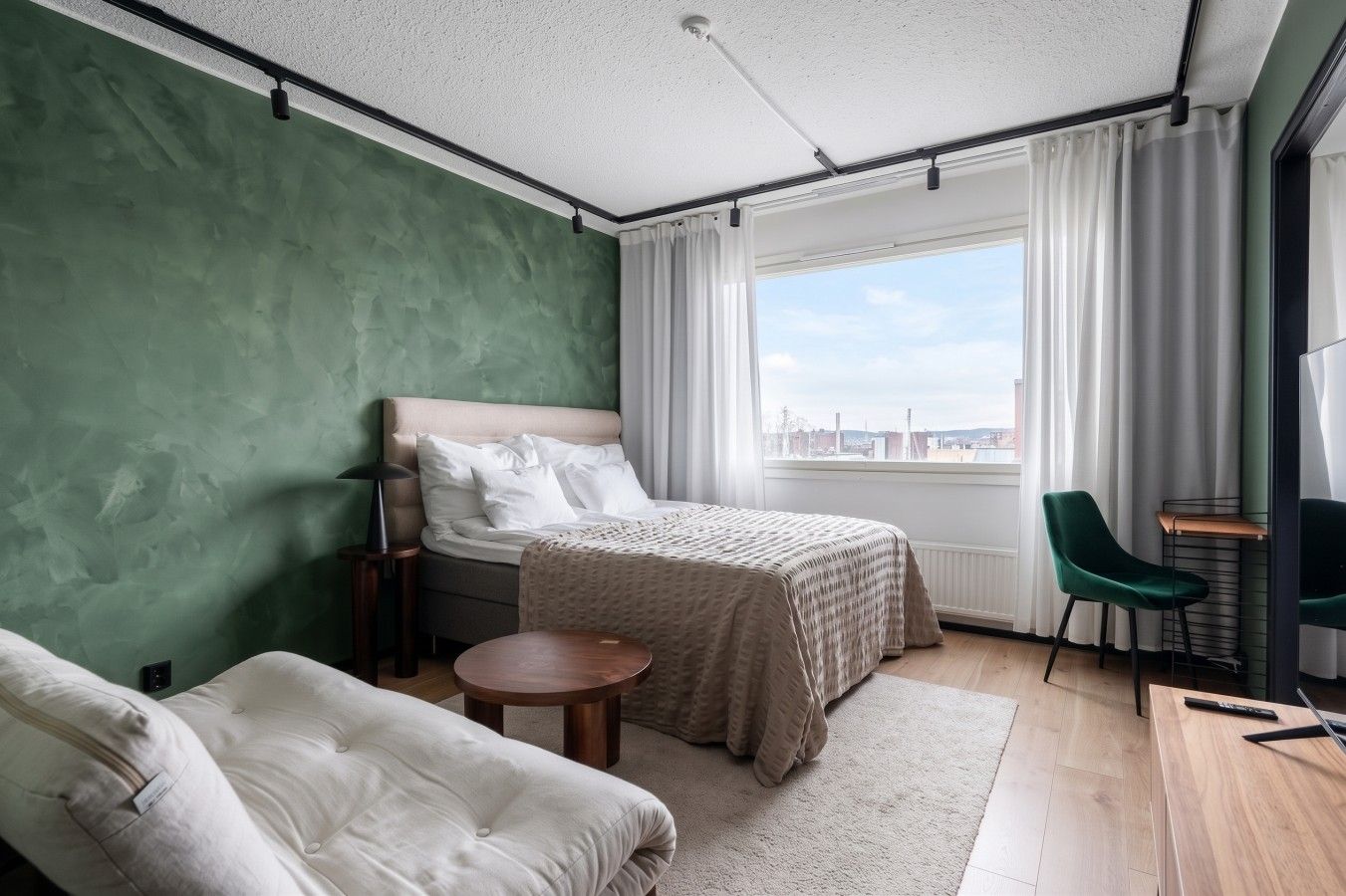 Habitación de hotel moderna con cama, zona de estar y vistas a la ciudad.