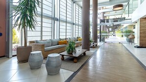 Een ruime lobby met een grote bank, een bijzettafeltje en decoratieve vazen.