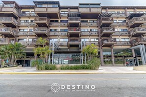 A multi-story hotel with balconies, a covered entrance, and a sign for 'DESTINO GESTAO EM HOSPITALIDADE'. - Cobertura Beira-Mar | 4 Quartos | Varanda Gourmet e Churrasqueira | Barra Bali | Destino BSM 418 (Barra de São Miguel)