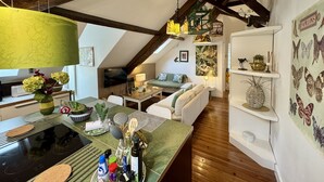 Un acogedor espacio tipo loft con zona de cocina, vigas de madera, una mesa de comedor y varios objetos decorativos.