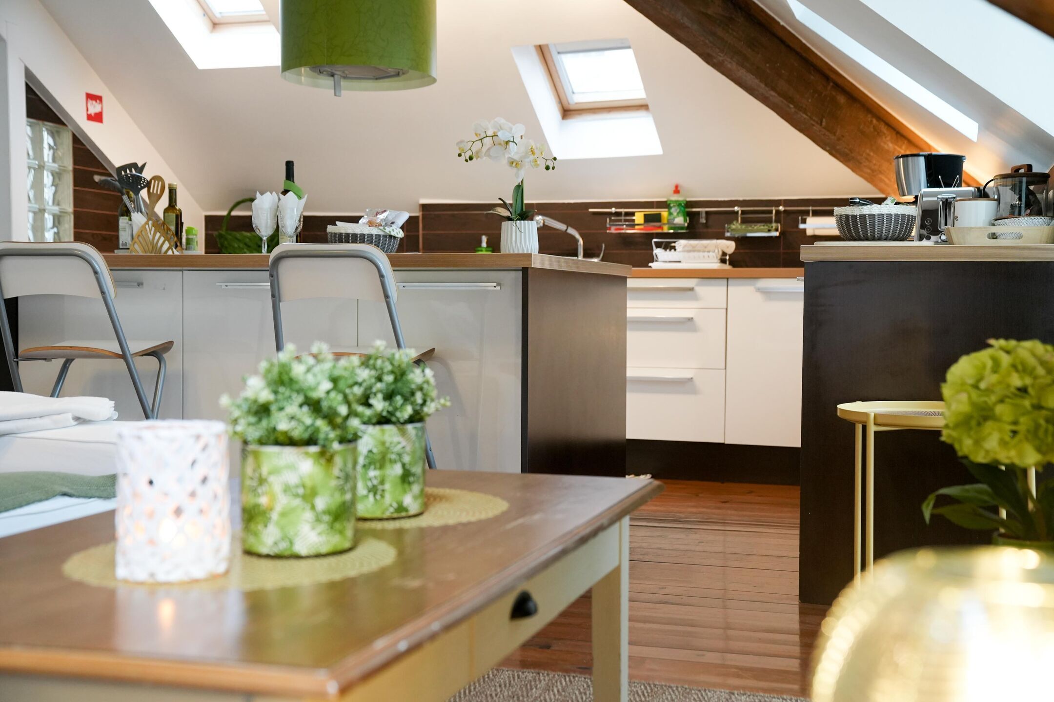 Een moderne keuken met dakramen, een eethoek met een tafel, en uitzicht op de woonkamer.