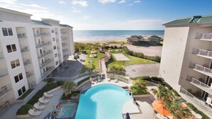 Un complexe hôtelier doté d’une piscine, offrant une vue sur la plage et comprenant plusieurs balcons.