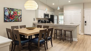 Une cuisine moderne avec des meubles blancs, un îlot central et des luminaires suspendus.