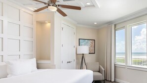 Une chambre d’hôtel comprenant un lit, un ventilateur de plafond, un bureau, une chaise, une fenêtre avec vue et une porte.