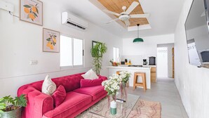 A modern living room with a red sofa, a glass coffee table, and a ceiling fan. - Cool house with Pool at only steps from the Beach and Surf (Carmen Beach)