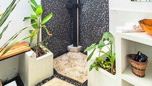 A modern bathroom with a shower, white walls, a black textured partition, and various potted plants. - Cool house with Pool at only steps from the Beach and Surf (Carmen Beach)