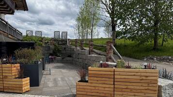 A paved outdoor area with wooden planters and a stone wall.