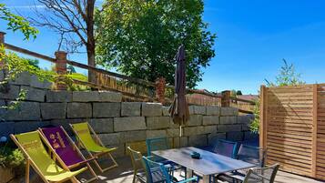 An outdoor patio with stone walls, a wooden fence, and a table with chairs.