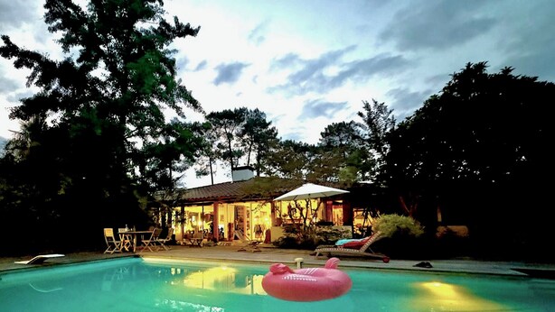 Une piscine avec des chaises longues et un flotteur gonflable rose.