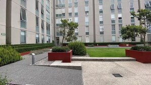 Un bâtiment moderne à plusieurs étages, doté de grandes fenêtres et d’une cour bien entretenue, agrémentée d’espaces paysagers et d’arbres.