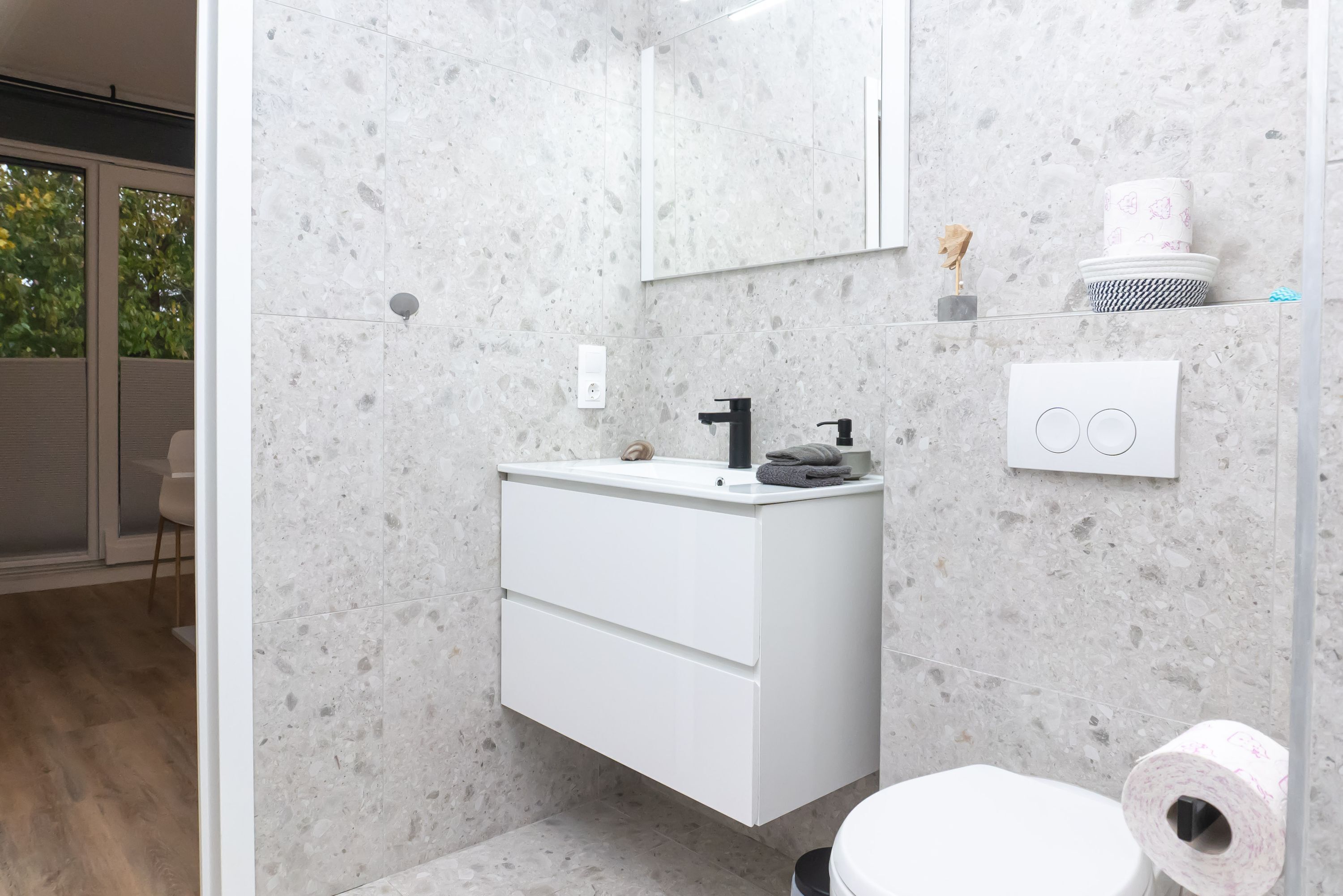 A modern bathroom with a white vanity, a mirror, and a toilet.