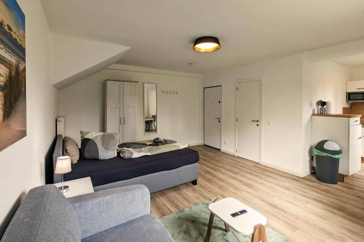 Un espace de vie compact comprenant un lit, un canapé, une petite table et un coin cuisine.