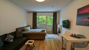 Un dormitorio moderno con cama, sofá, una mesita y escritorio.