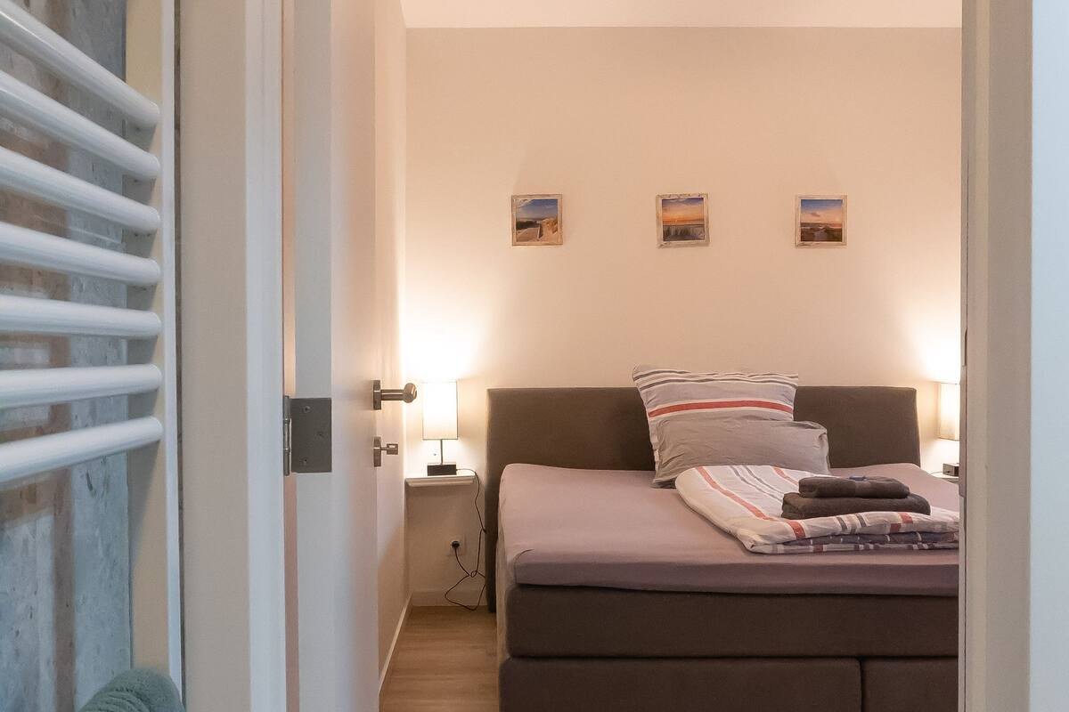 Une chambre à coucher comprenant un lit, des lampes de chevet, une table de chevet et un radiateur fixé au mur.