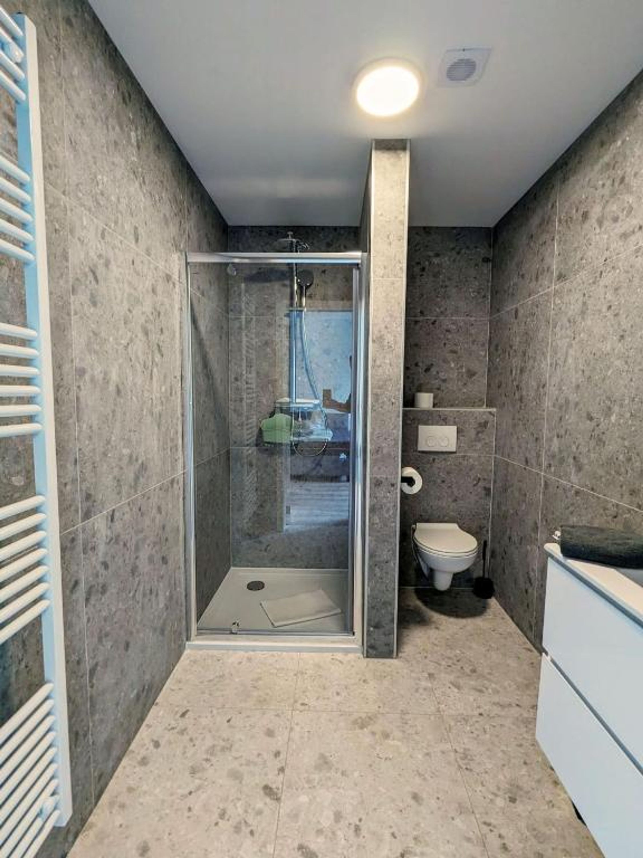Ein modernes Badezimmer mit einer gläsernen Duschkabine, einer Toilette und einer Badewanne.