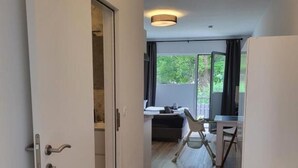 Un pasillo con suelo de madera, un escritorio con silla y una ventana con cortinas.