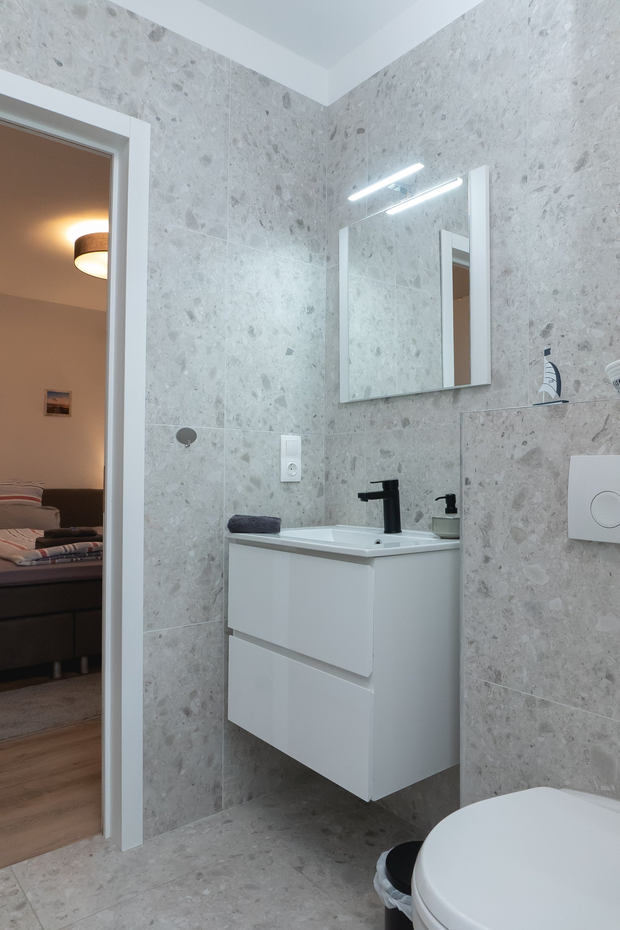 A modern bathroom with a white vanity, a mirror, and a toilet.