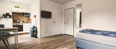 Un espacio habitable compacto con kitchenette, comedor, sofá y televisor.