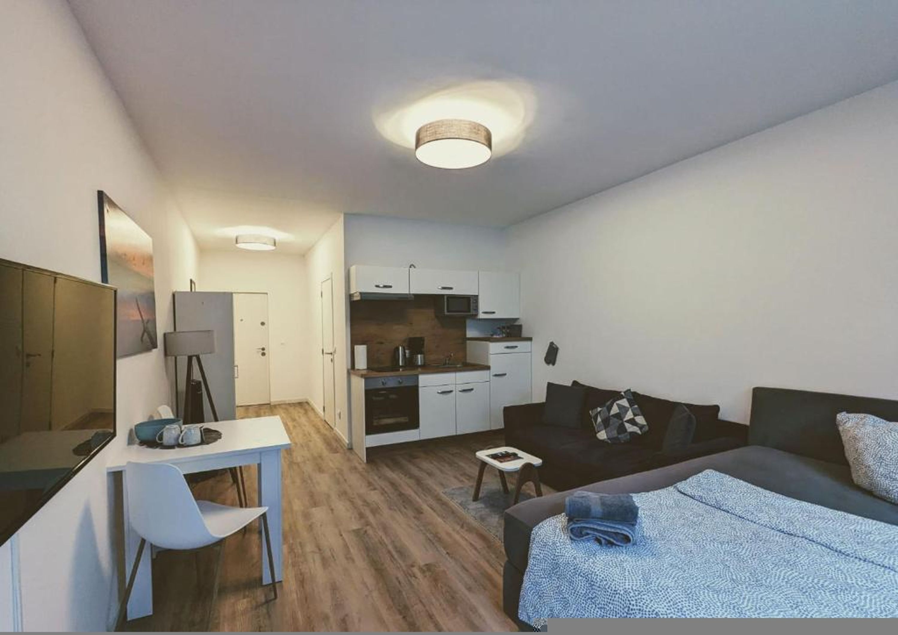 Ein kompakter Wohnbereich mit Küchenzeile, Essbereich und einem Bett.