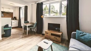 Un espacio habitable compacto con kitchenette, comedor, televisor y sofá.