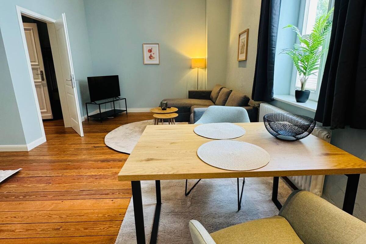 Un salon moderne comprenant un coin repas, un téléviseur, une lampe et une fenêtre avec des rideaux.