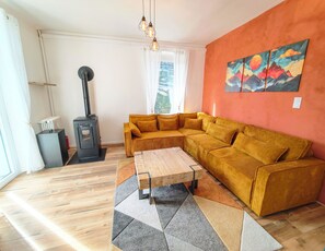 A living room with a sofa, a coffee table, a fireplace, and a painting on the wall. - Le Bleuet - 5mn walk from the lake - Private parking lot (Aix-les-Bains)