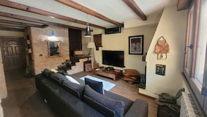 Een woonkamer met een bank, een televisie en een trap naar een andere kamer.