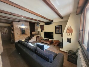 Ein Wohnzimmer mit Sofa, Fernseher und einer Treppe, die in einen anderen Raum führt.