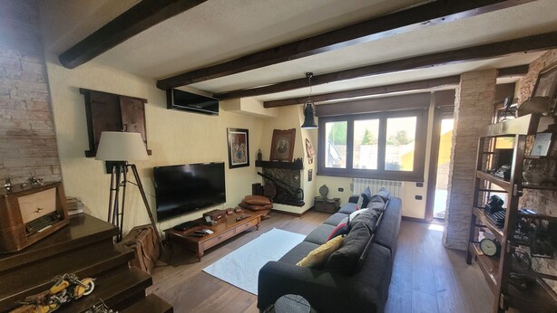 Een woonkamer met een televisie, bank en een open haard.