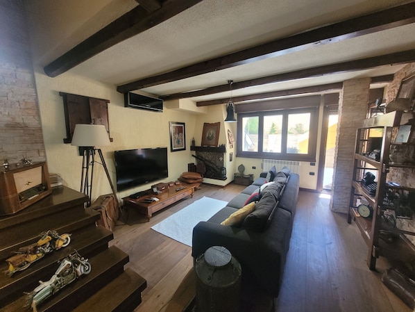 Ein Wohnzimmer mit Fernseher, Sofa und Kamin.