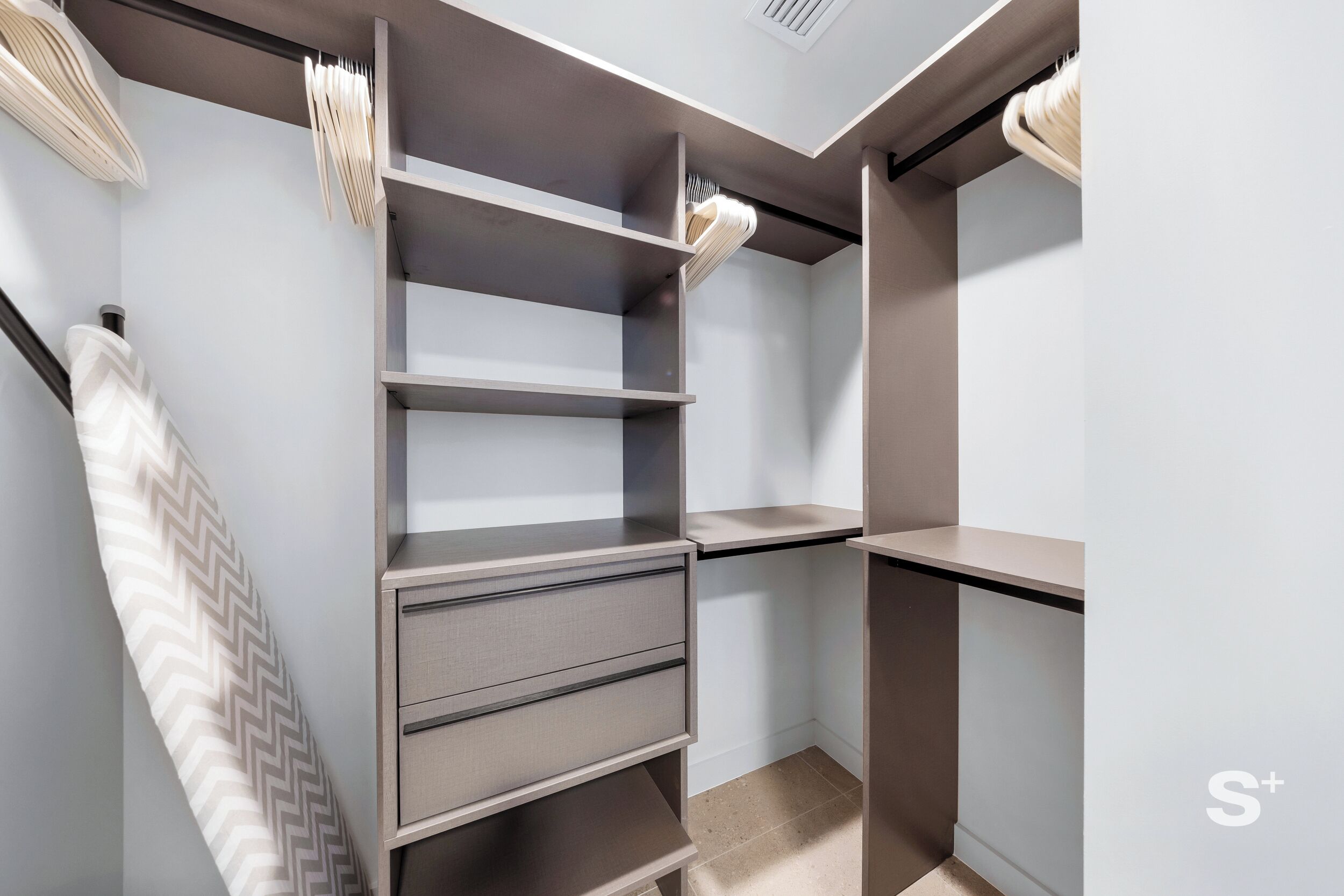 Ein moderner Kleiderschrank mit mehreren Regalen und Schubladen, einer Kleiderstange und einem Handtuch mit Zickzackmuster.