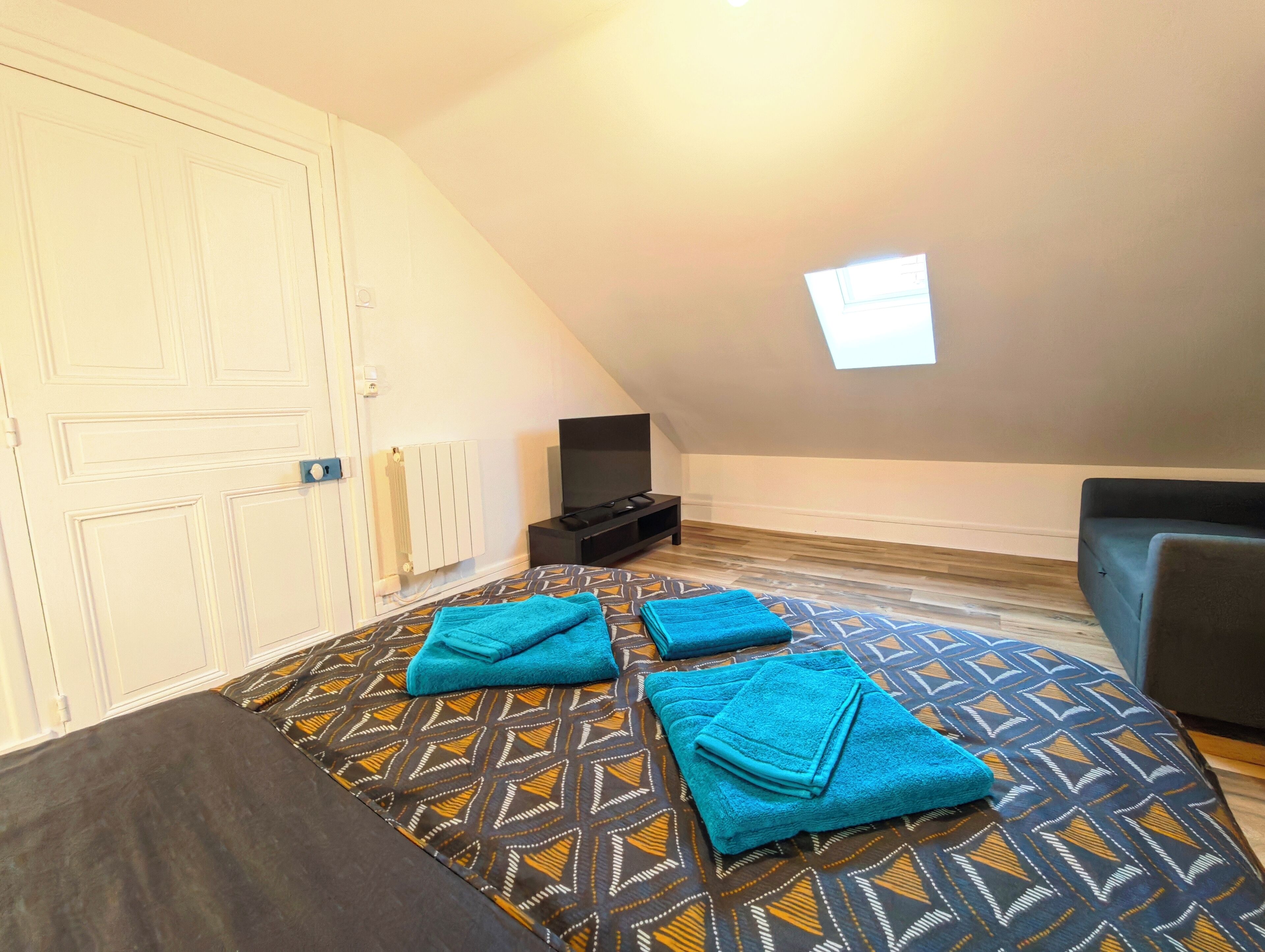 A bedroom with a bed, a TV, a window, and a door.