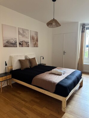 A bedroom with a wooden bed, a bedside table, a lamp, and wall art. - Fabulous 4-bedroom apartment in Paris perfect for your getaway (Paris)